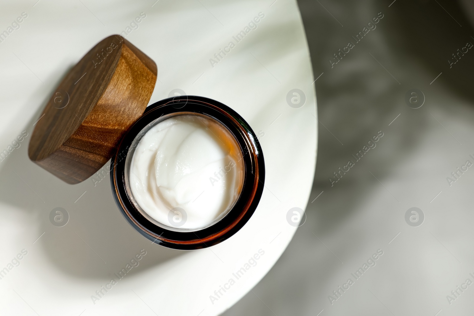 Photo of Open jar of cosmetic cream on white table, top view. Space for text