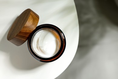 Open jar of cosmetic cream on white table, top view. Space for text