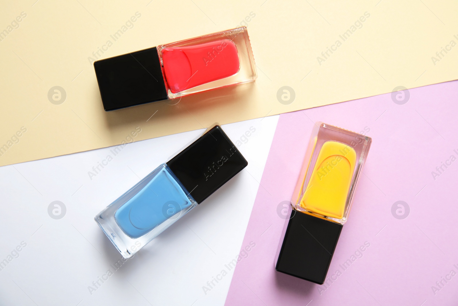 Photo of Bottles of nail polish on color background, top view