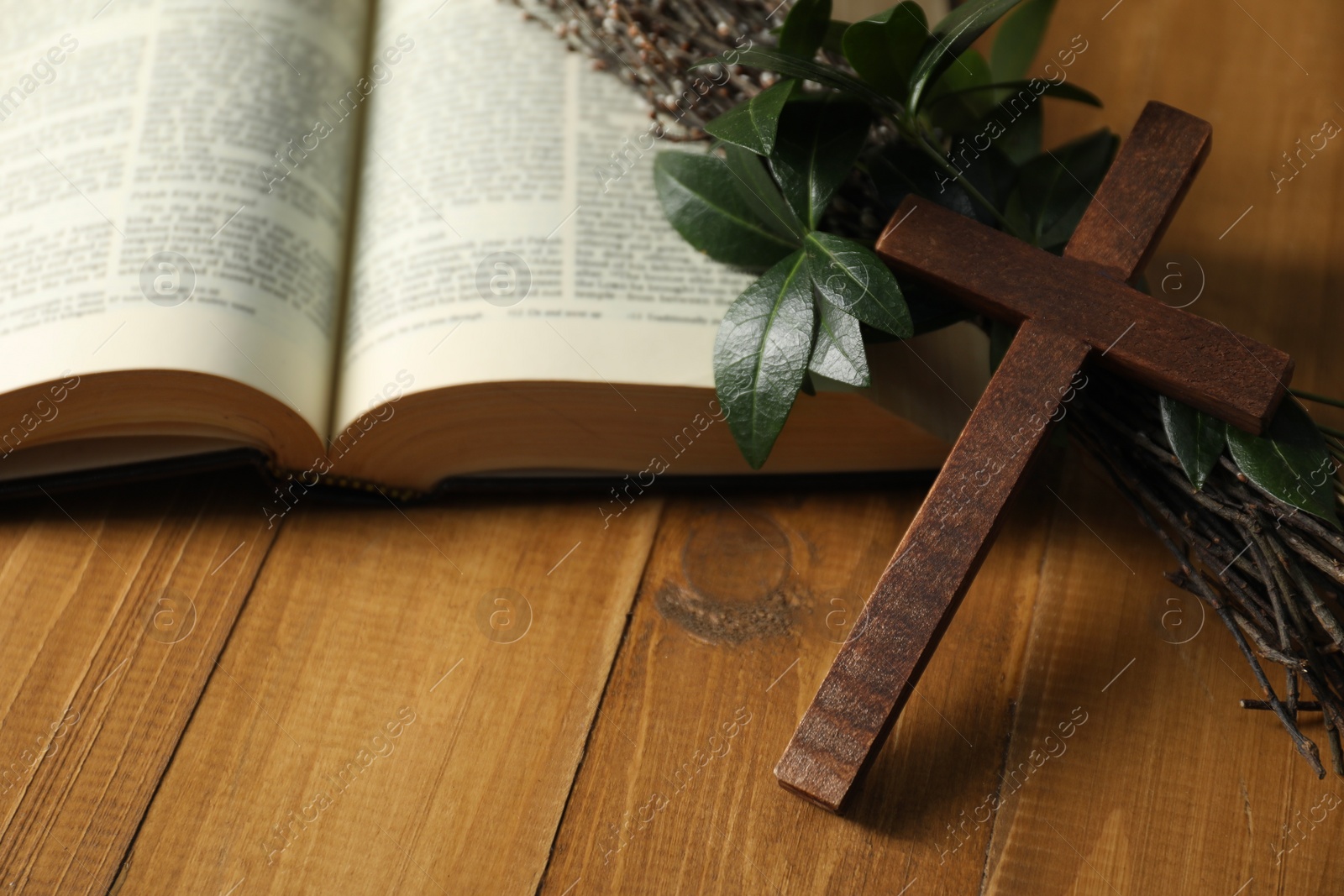 Photo of Cross, Bible and green leaves with willow branches on wooden table