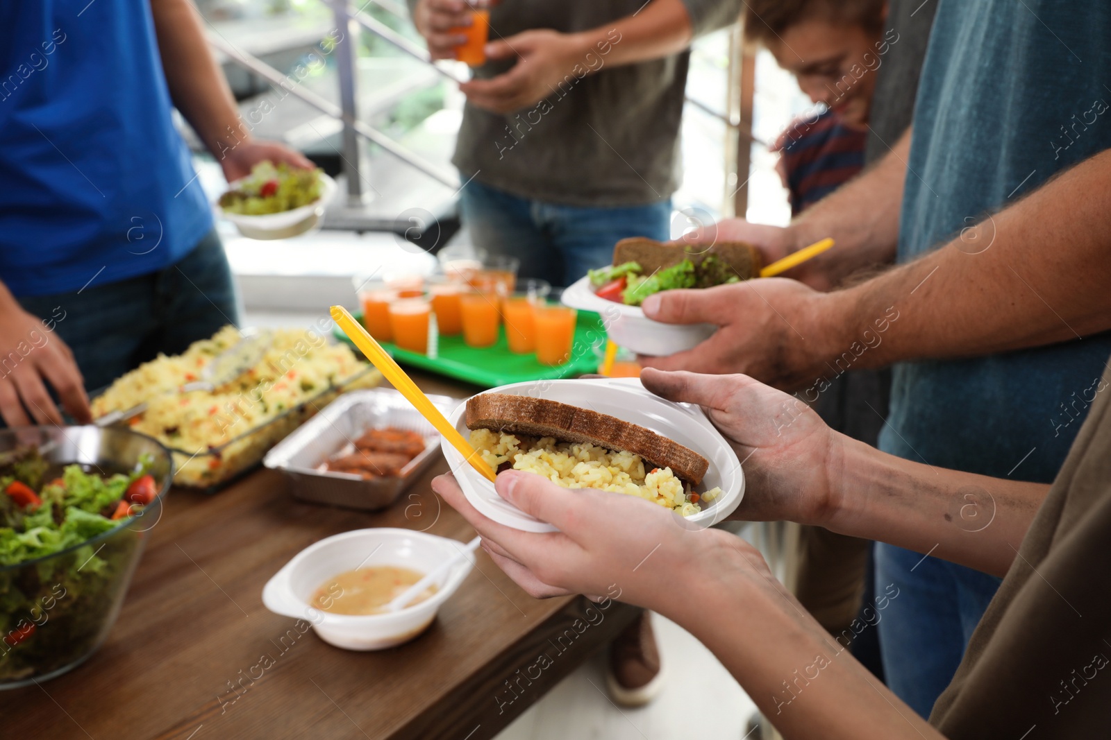 Photo of Poor people receiving food from volunteer in charity centre, closeup