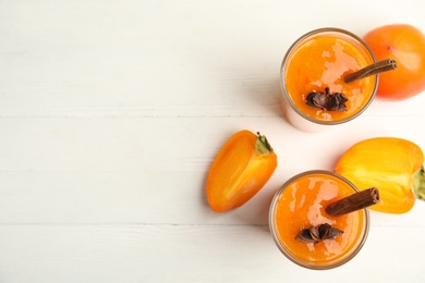 Tasty persimmon smoothie with anise and cinnamon on white wooden table, flat lay. Space for text