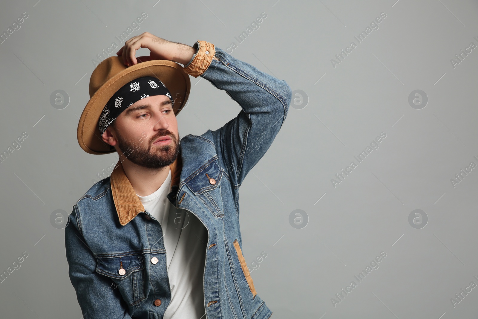 Photo of Fashionable young man in stylish outfit with bandana on grey background, space for text