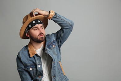 Fashionable young man in stylish outfit with bandana on grey background, space for text