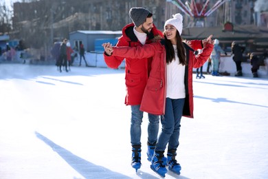 Image of Lovely couple spending time together at outdoor ice skating rink