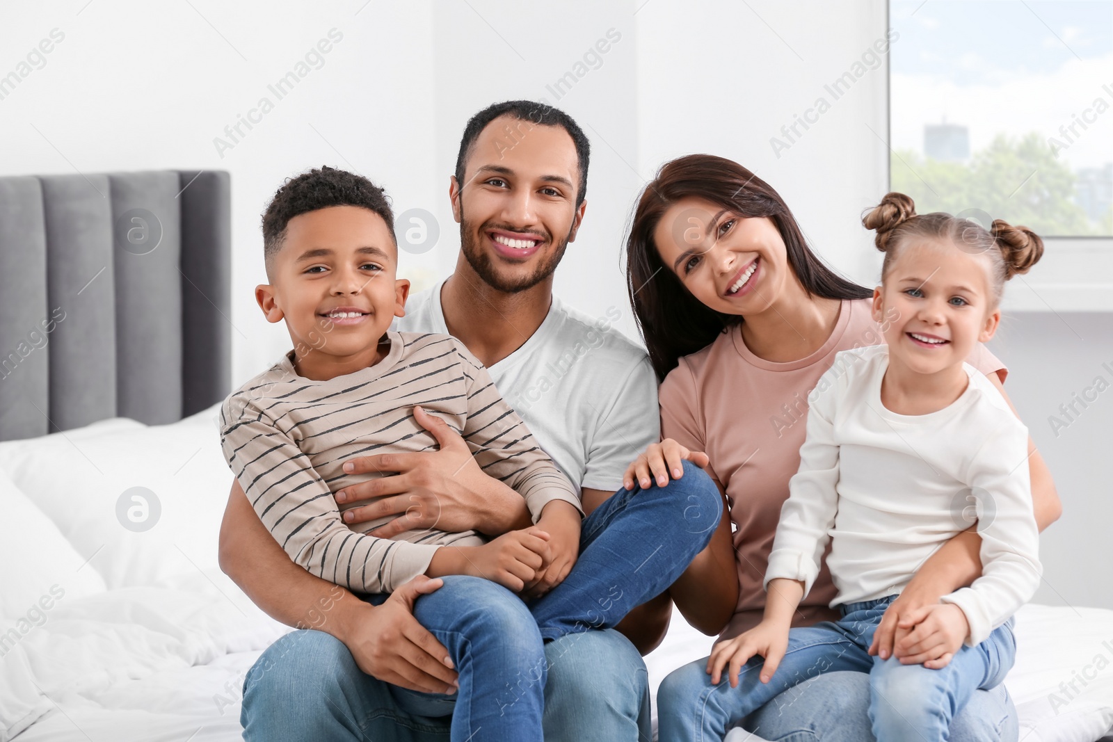 Photo of Happy international family spending time together on bed at home