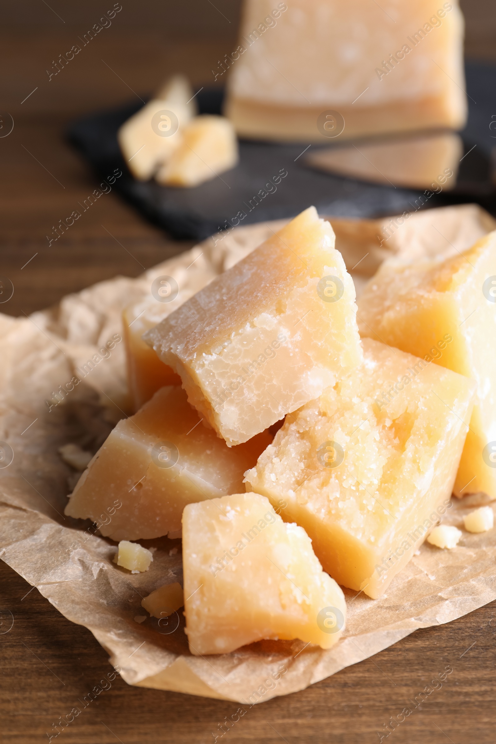 Photo of Pieces of delicious parmesan cheese on wooden table, closeup