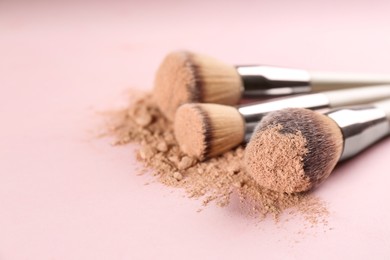 Different makeup brushes with crushed cosmetic product on pink background, closeup. Space for text