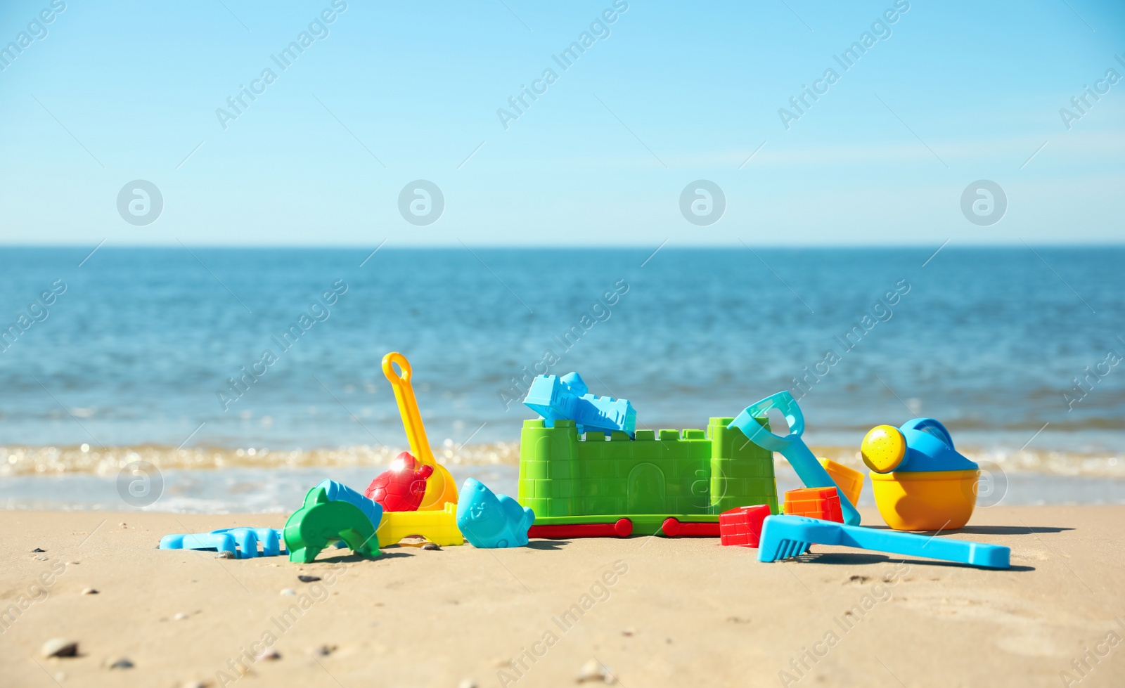 Photo of Different child plastic toys on sandy beach. Space for text