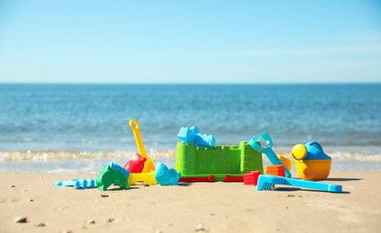 Different child plastic toys on sandy beach. Space for text