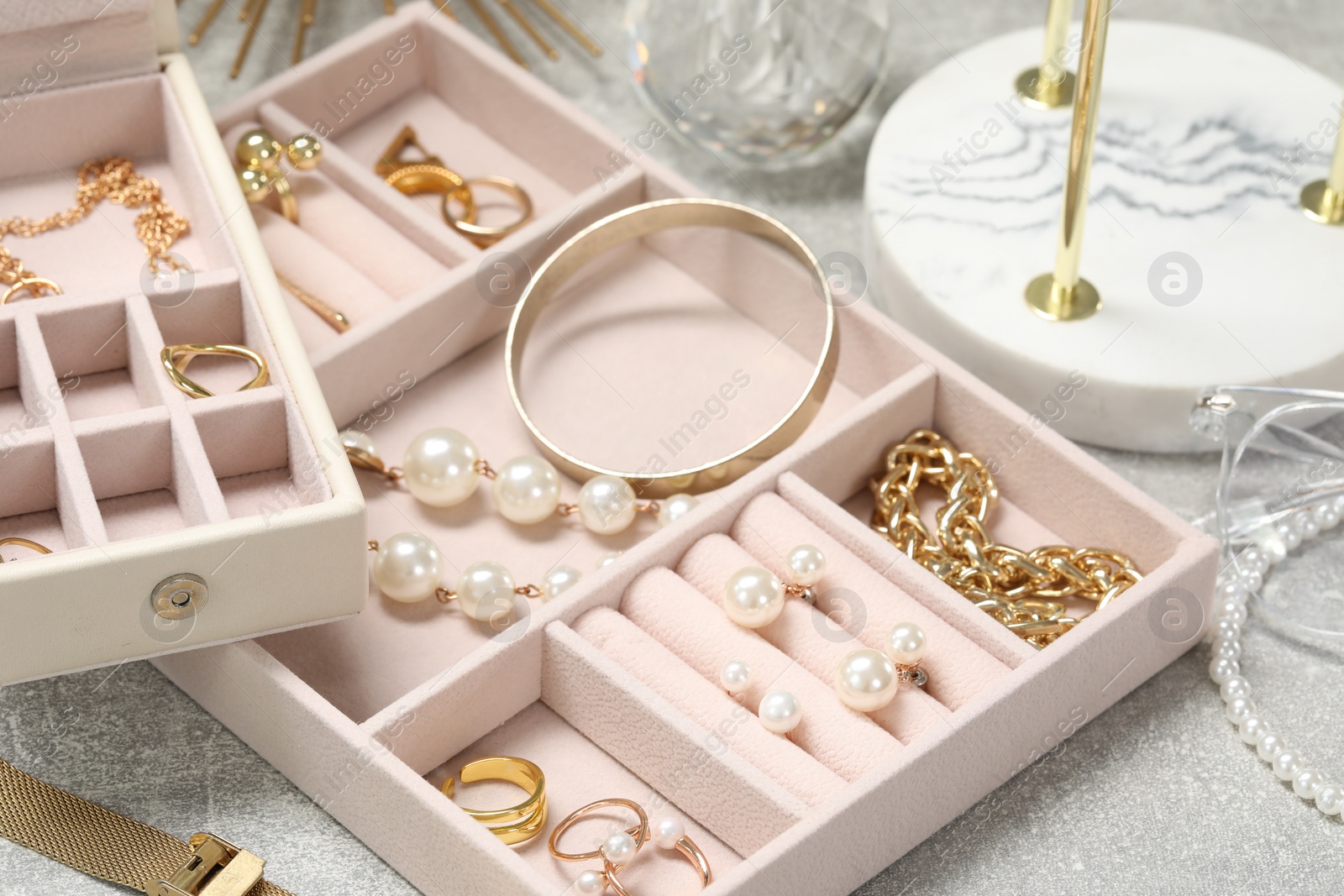 Photo of Jewelry boxes with many different accessories on light grey table, closeup