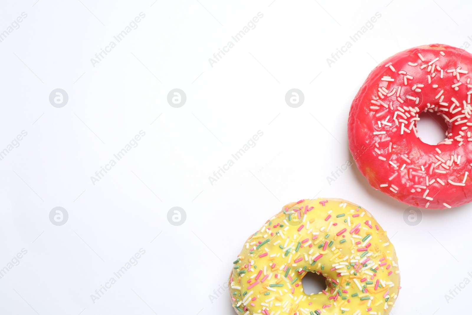 Photo of Delicious glazed donuts on white background, flat lay. Space for text