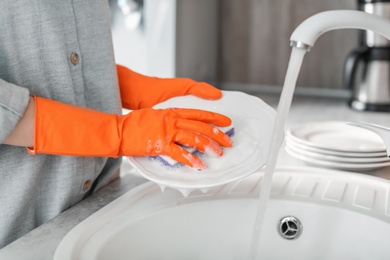 Young woman washing dishes in kitchen