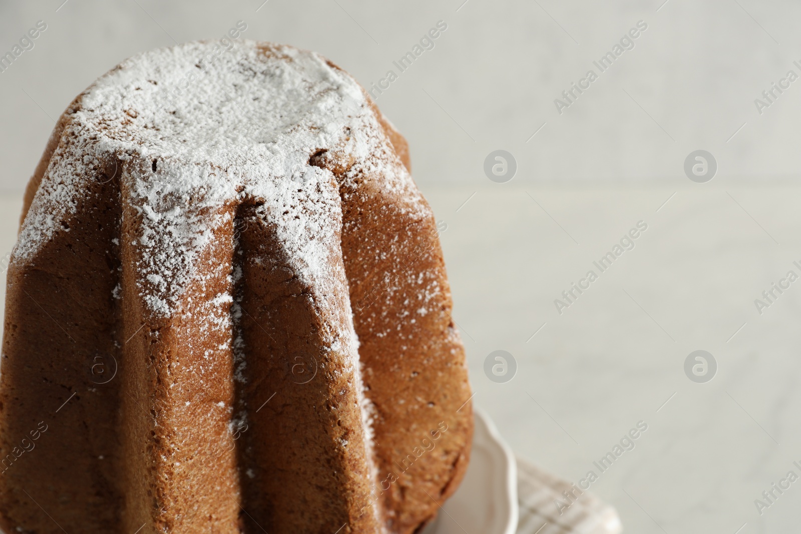 Photo of Delicious Pandoro cake decorated with powdered sugar on table, closeup and space for text. Traditional Italian pastry