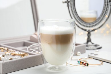 Photo of Delicious latte near jewelry box on white table