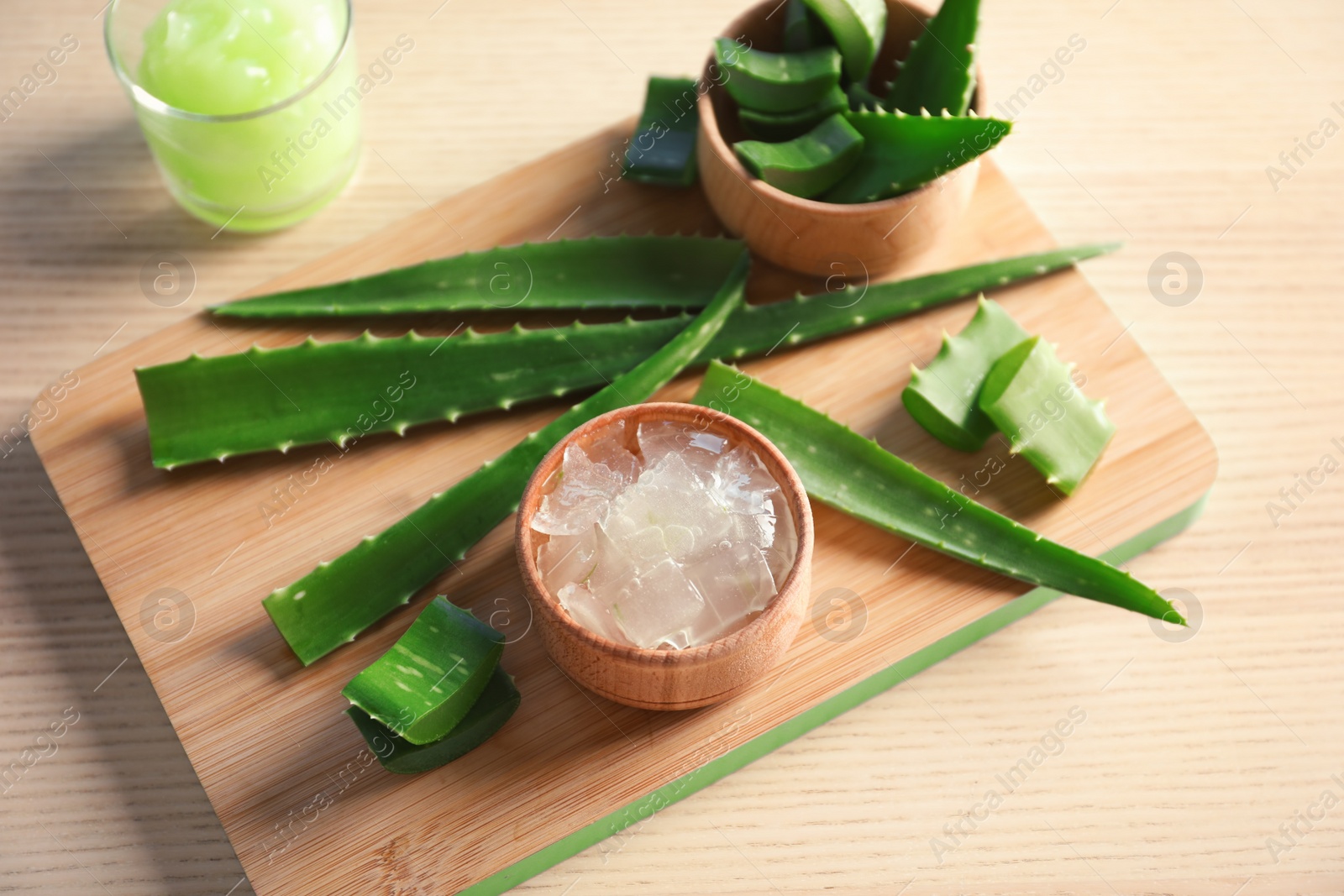 Photo of Bowl with peeled aloe vera and green leaves on wooden board