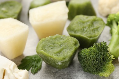 Photo of Frozen cauliflower and broccoli puree cubes on light grey table, closeup