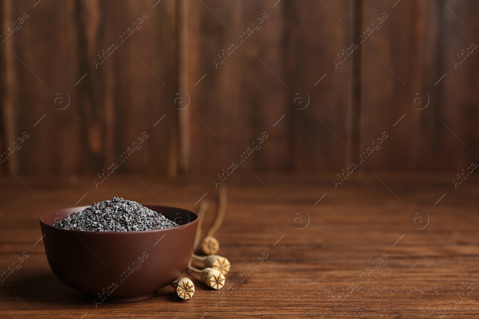 Photo of Bowl with poppy seeds on wooden table