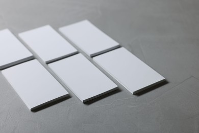 Blank business cards on light grey textured table, closeup. Mockup for design