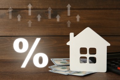 Image of Mortgage. House model, money, arrows and percent sign on wooden background
