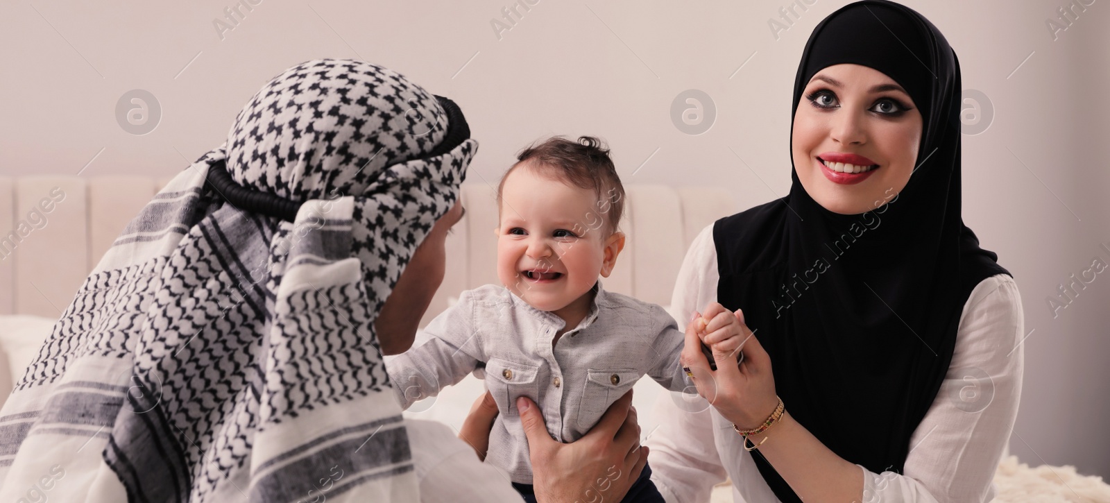 Image of Happy Muslim family with little son in bedroom. Banner design 