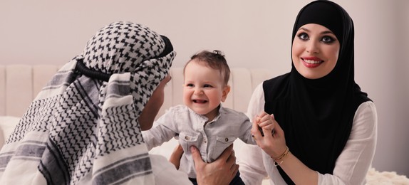 Happy Muslim family with little son in bedroom. Banner design 