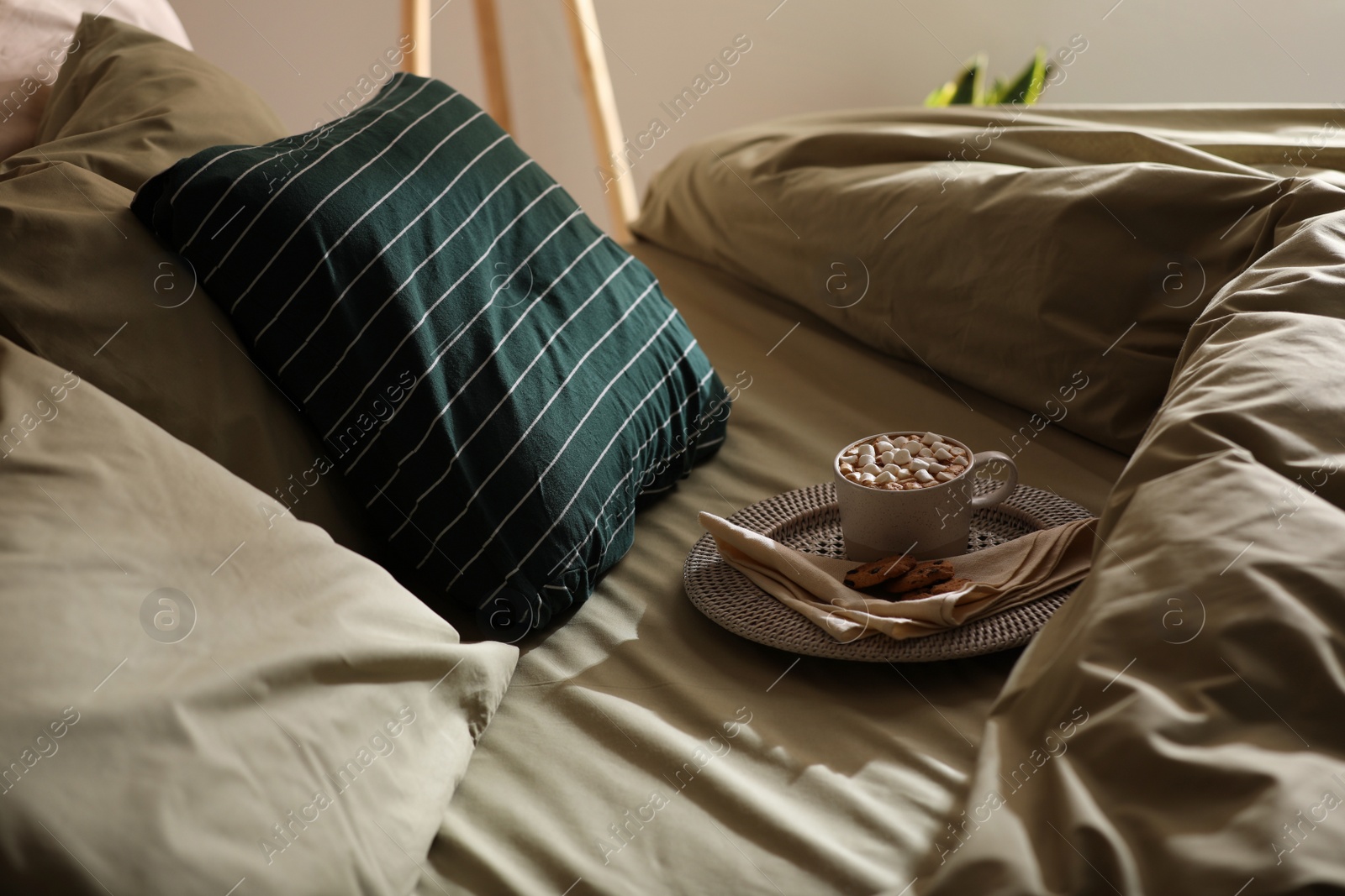 Photo of Cup of drink and cookies on bed with new pistachio linens in room