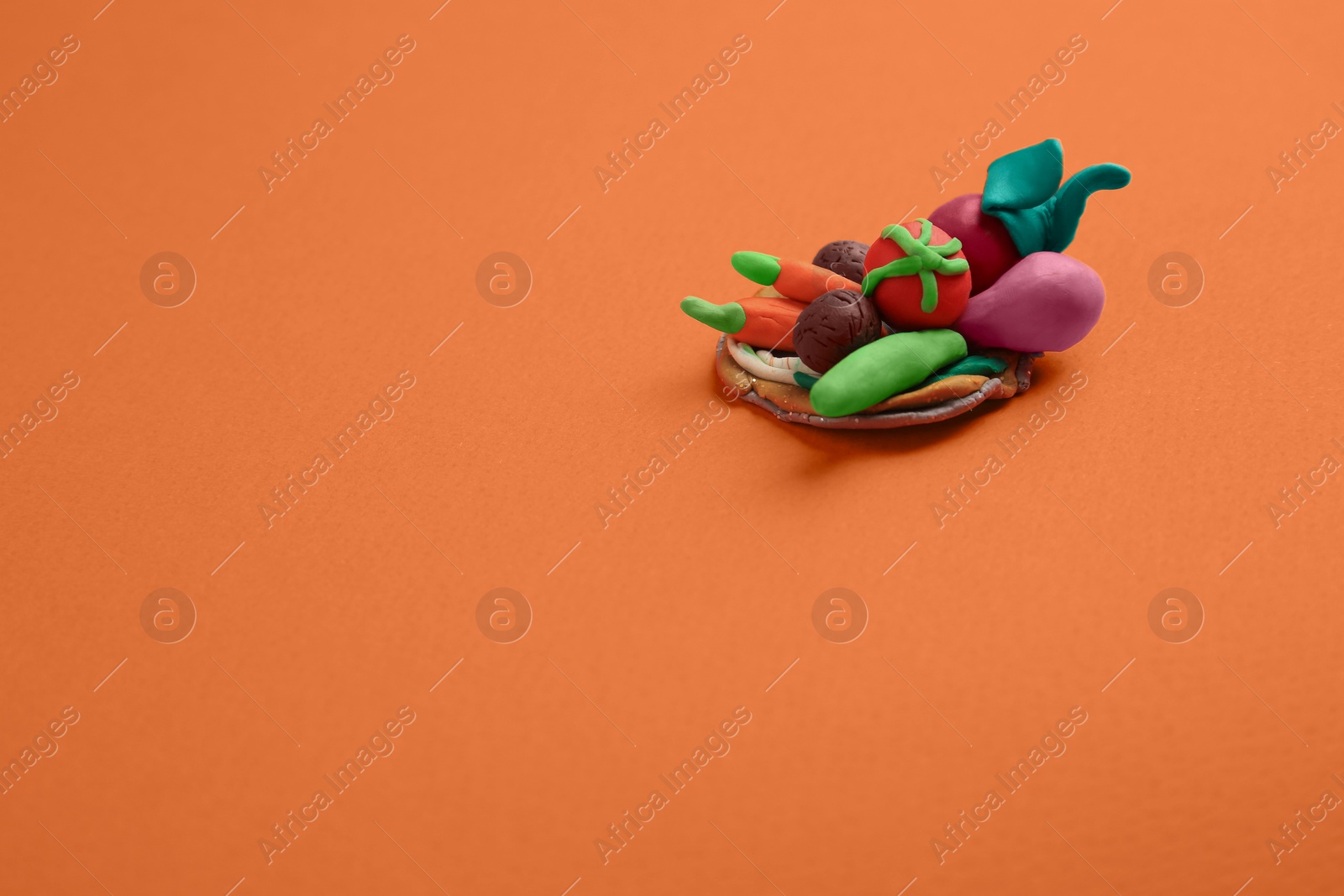 Photo of Different plasticine vegetables on orange background, above view with space for text. Children's handmade ideas