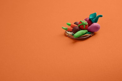 Photo of Different plasticine vegetables on orange background, above view with space for text. Children's handmade ideas