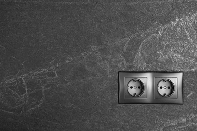 Photo of Power sockets on dark grey wall, space for text. Electrical supply