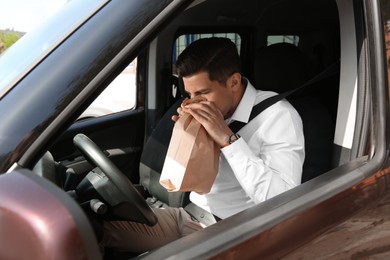 Photo of Man with paper bag suffering from nausea in car