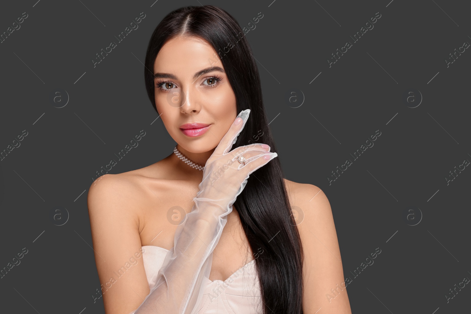 Photo of Portrait of beautiful young woman in evening gloves on black background