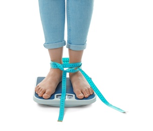 Photo of Woman with tape measuring her weight using scales on white background. Healthy diet
