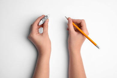 Photo of Woman holding pencil and eraser on white background, top view