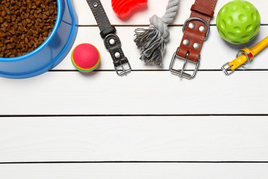Photo of Flat lay composition with dog collars, toys and food on white wooden table. Space for text