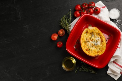 Photo of Half of cooked spaghetti squash with cheese in baking dish on black table, flat lay. Space for text