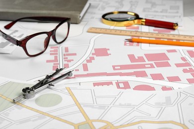 Photo of Office stationery and eyeglasses on cadastral maps of territory with buildings