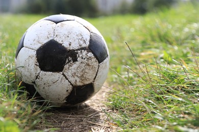 Photo of Dirty soccer ball on green grass outdoors, closeup. Space for text