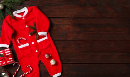Photo of Flat lay composition with cute Christmas baby clothes on wooden background. Space for text
