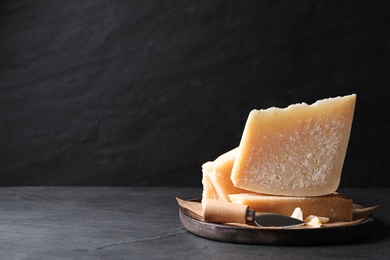 Delicious parmesan cheese with knife on black table. Space for text