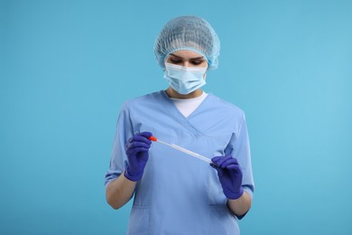 Photo of Laboratory testing. Doctor with cotton swab and tube on light blue background