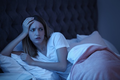 Photo of Young woman suffering from insomnia in bed at night. Sleeping problems