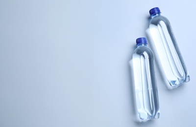 Photo of Plastic bottles with water on white background, flat lay. Space for text