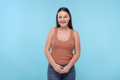 Photo of Smiling woman with dental braces on light blue background