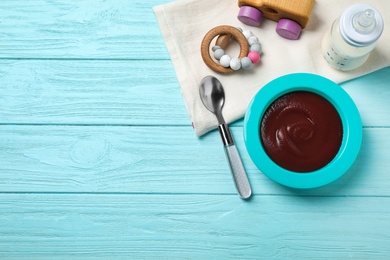 Photo of Flat lay composition with bowl of healthy baby food on light blue wooden table. Space for text