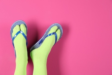 Photo of Woman wearing bright socks with flip-flops and space for design on color background