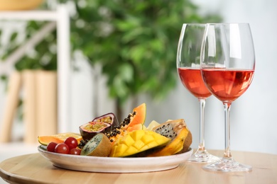 Delicious exotic fruits and glasses of wine on wooden table indoors