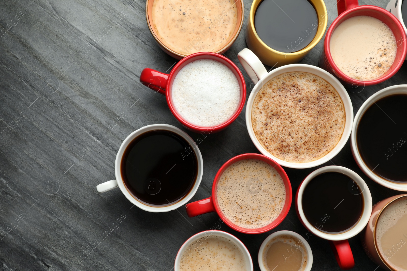 Photo of Many cups of different coffees on slate table, flat lay