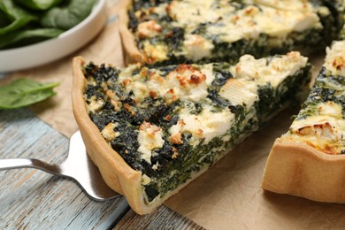 Photo of Taking piece of delicious homemade spinach quiche on table, closeup