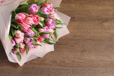 Photo of Bouquet of beautiful tulips on wooden table, closeup. Space for text